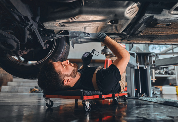 car mechanic worker working using wrench tool for repair, maintenance underneath car